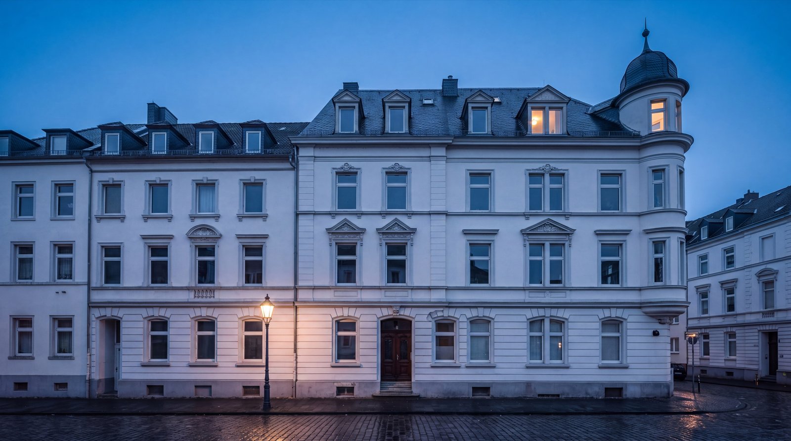 Gründerzeitfassade von 1904 mit Turm, Schieferdach und dunkler Eichenhaustür in der blauen Stunde